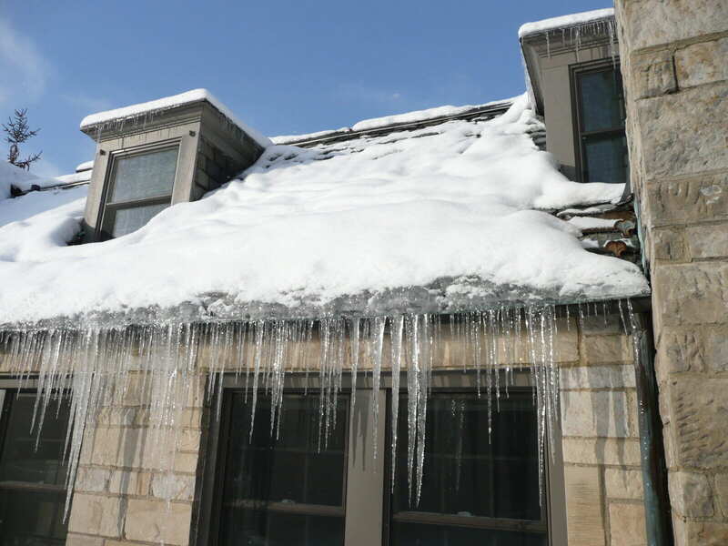 Thick ice dam built up along a roof eave in winter